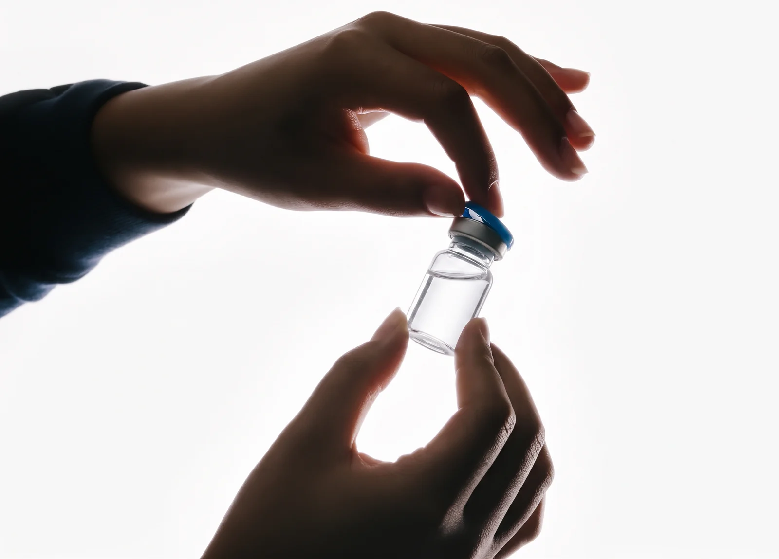Lab testing: hands opening an unlabeled clear medication vial